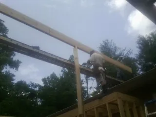 Carpenter setting a ridge beam over a new addition frame — Ice Dam Removal by Roofing Brothers in Camp Lejeune