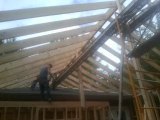 Rafters going up over a new addition with a worker on the wall in Camp Lejeune