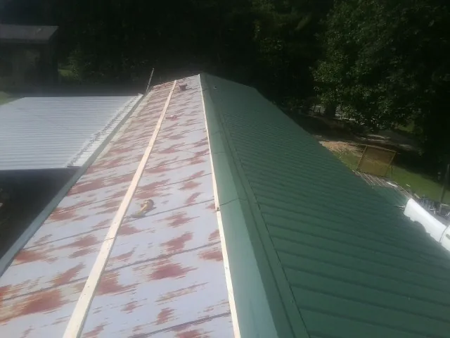 Old rusted panels beside newly installed green metal roofing — Wind Damage Roof Repair by Roofing Brothers in Camp Lejeune