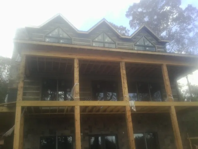 Dormers and porch framing on a large log home under construction — Roof Coating work by our crew in Camp Lejeune