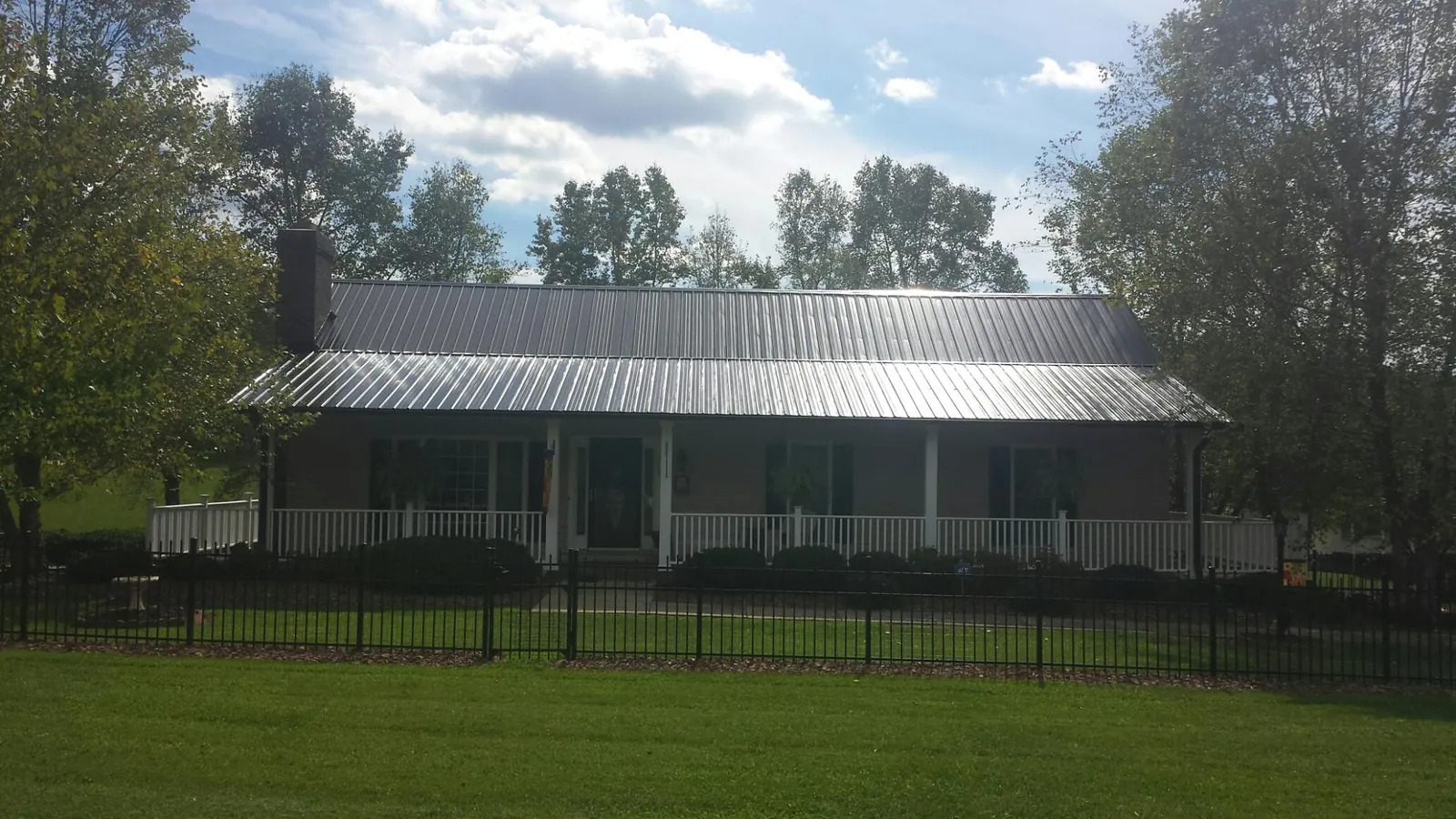 Gray metal roof on a brick ranch with a full width front porch — Gutter Guard Installation work by our crew in Camp Lejeune