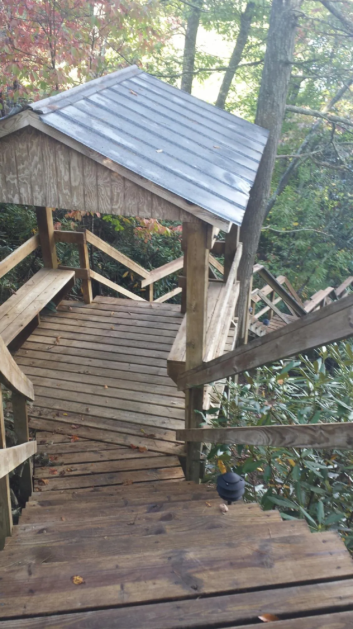 Metal roofed shelter over wooden steps on a wooded walkway — Skylight Repair & Installation work by our crew in Camp Lejeune