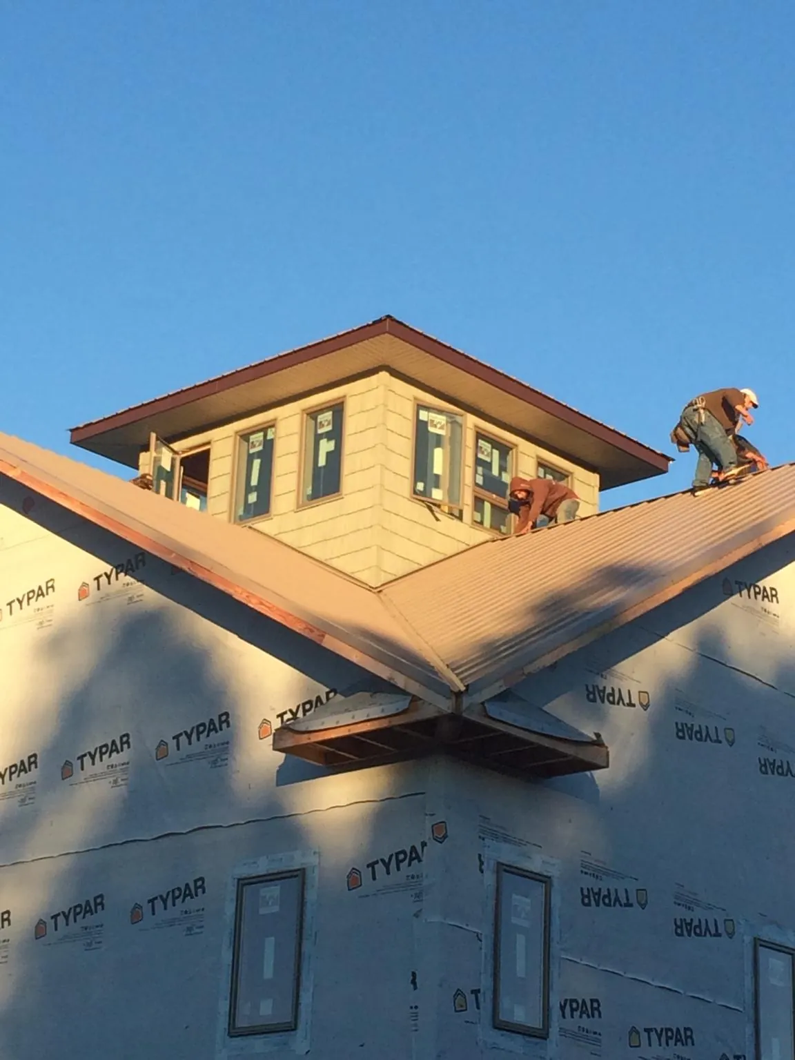 Roofers working around a rooftop cupola on a new metal roof at sunset — Roof Waterproofing in Camp Lejeune by Roofing Brothers
